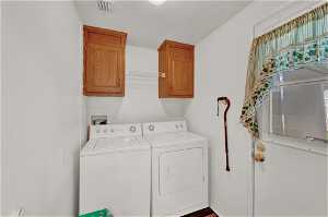 Clothes washing area featuring cabinets, hookup for a washing machine, and washer and clothes dryer