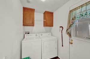 Clothes washing area featuring cabinets, hookup for a washing machine, and washer and clothes dryer