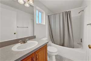 Full bathroom with tile floors, shower / tub combo, vanity, and toilet