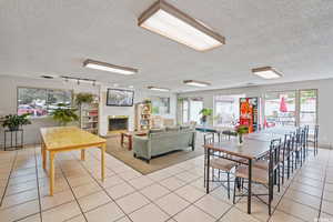 Dining room featuring light tile patterned flooring, a fireplace, a textured ceiling, and track lighting