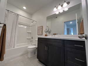 Full bathroom featuring shower / bathtub combination with curtain, toilet, tile flooring, and vanity