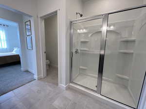 Bathroom featuring a shower with shower door, tile floors, and toilet