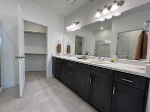 Bathroom featuring dual sinks, tile flooring, and large vanity