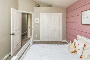 Unfurnished bedroom with vaulted ceiling, carpet flooring, and a closet