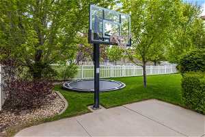 View of basketball court with a trampoline and a lawn