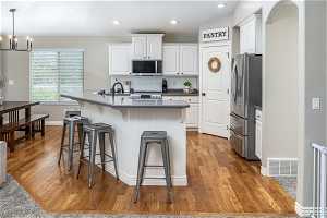 Kitchen featuring light hardwood / wood-style flooring, stainless steel appliances, an island with sink, white cabinets, and sink