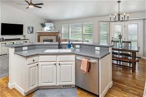 Kitchen with sink, vaulted ceiling, dishwasher, and an island with sink