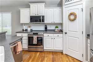 Kitchen with white cabinets, stainless steel appliances, and light wood-type flooring