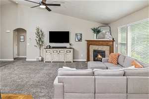 Carpeted living room with high vaulted ceiling, ceiling fan, and a tile fireplace