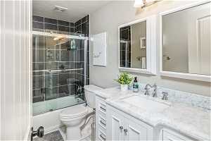 Full bathroom featuring vanity, bath / shower combo with glass door, tile flooring, toilet, and a textured ceiling