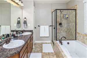 Bathroom featuring vanity with extensive cabinet space, double sink, separate shower and tub, a wealth of natural light, and tile floors