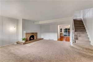 Unfurnished living room with carpet flooring and a brick fireplace