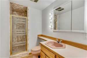 Bathroom with a shower with shower door, vanity with extensive cabinet space, and toilet