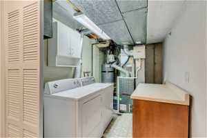 Laundry room with separate washer and dryer, cabinets, light tile floors, and gas water heater