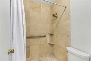 Bathroom with a shower with shower curtain and toilet