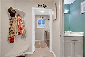 Mudroom featuring sink, light tile floors, and washer and clothes dryer