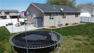 Rear view of property featuring a yard, a patio area, and a trampoline