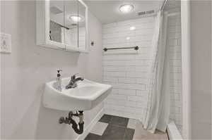 3/4 bathroom with curtained shower and tile floors.