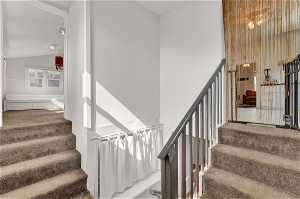 Stairs featuring vaulted ceiling and carpet floors