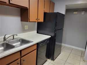 Kitchen with sink, refrigerator, light tile floors, and black dishwasher