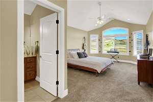 Bedroom with light colored carpet, connected bathroom, ceiling fan, and vaulted ceiling