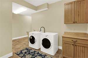 Clothes washing area featuring sink, washer and dryer, cabinets, and tile floors