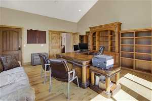 Office space with light hardwood / wood-style flooring and high vaulted ceiling