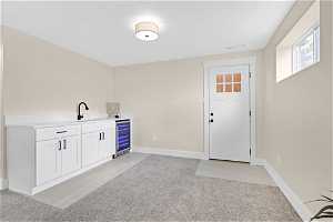 Interior space with light colored carpet, white cabinets, and beverage cooler
