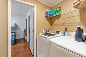 Washroom featuring ornamental molding, washer hookup, dark hardwood / wood-style floors, and washer and clothes dryer