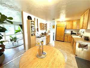 Kitchen featuring paneled fridge, sink, light tile floors, and white range with gas stovetop