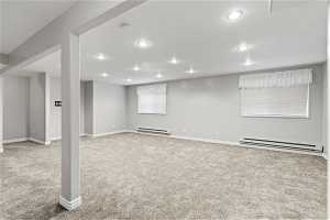 Basement with a baseboard radiator and carpet flooring