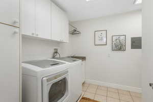 Laundry area with sink, separate washer and dryer, cabinets, and light tile floors