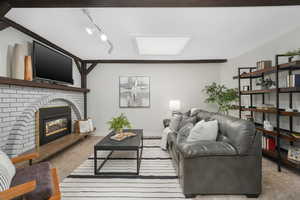 Living room featuring a skylight, track lighting, and a brick fireplace