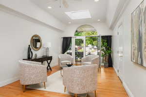 Sitting room featuring lofted ceiling with skylight, ceiling fan, and light  flooring