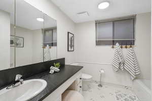 Bathroom with tile floors, vanity with extensive cabinet space, and toilet