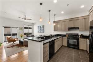 Kitchen featuring dark tile floors, black appliances, kitchen peninsula, sink, and ceiling fan