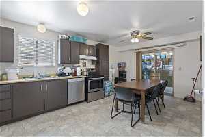 Kitchen featuring ceiling fan, sink, stainless steel appliances, and light tile flooring