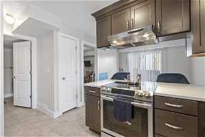 Kitchen with dark brown cabinets, light tile floors, and stainless steel electric range oven