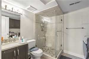 Bathroom featuring an enclosed shower, vanity, toilet, and tile flooring
