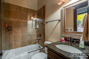 Bedroom 2 full bathroom with shower / bath combination with glass door, vanity, and toilet