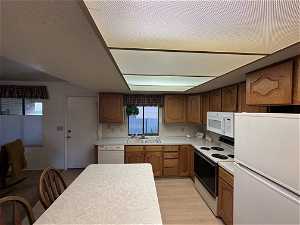 Kitchen featuring white appliances, tasteful backsplash, light hardwood / wood-style floors, and sink