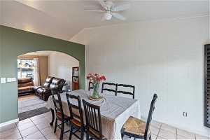 Dining space with crown molding, light tile floors, and vaulted ceiling.