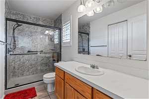 Master bathroom featuring a shower with door, toilet, tile floors, and vanity