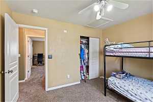 Carpeted bedroom with a closet, a textured ceiling, and ceiling fan