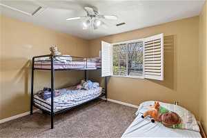 Bedroom with a textured ceiling, dark carpet, and ceiling fan