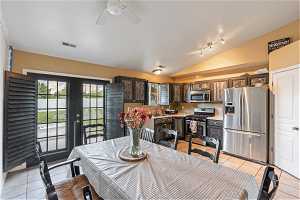 Dining area featuring french doors, ceiling fan, vaulted ceiling, light tile flooring, and rail lighting