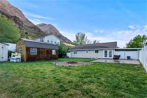 Back of property with a patio area, a lawn, a mountain view, and a storage shed