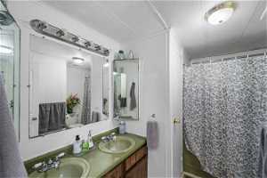 Bathroom featuring dual sinks, crown molding, a textured ceiling, and large vanity