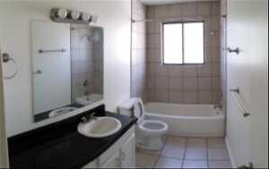 Full bathroom featuring tiled shower / bath combo, vanity with extensive cabinet space, tile floors, and toilet