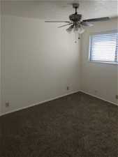 Empty room with ceiling fan, carpet, and a textured ceiling